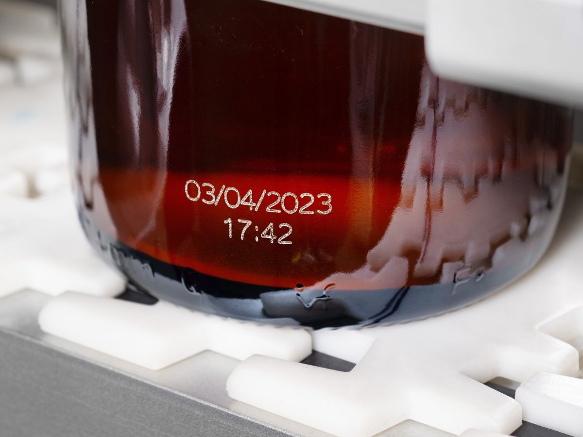 Laser-etched date and time code on an amber glass jar on the line